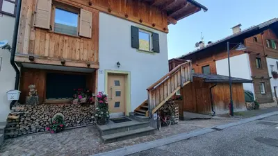 a house with a wooden staircase in front of it at Alex in Campitello di Fassa