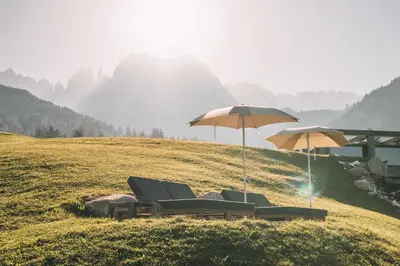 two chairs and umbrellas on a grassy hill at Cyprianerhof Dolomit Resort in Tires