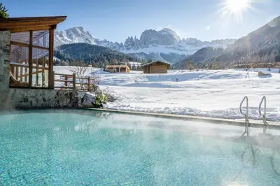 a swimming pool in the snow with mountains in the background at Cyprianerhof Dolomit Resort in Tires
