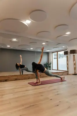 a woman doing a yoga pose in a yoga class at Cyprianerhof Dolomit Resort in Tires