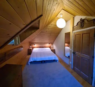 a large bedroom with a bed in a wooden attic at App. Lino nel cuore di Ortisei - casa dell'800 in Ortisei