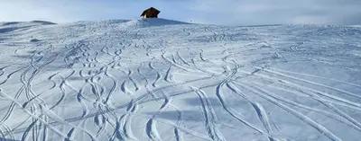 a snow covered hill with a house on top of it at App. Lino nel cuore di Ortisei - casa dell'800 in Ortisei