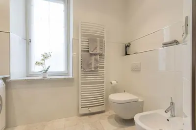 a white bathroom with a toilet and a window at Appartment Lissi in Merano