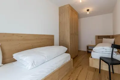 a bedroom with two beds and a chair in it at Casa Erika in San Lorenzo di Sebato