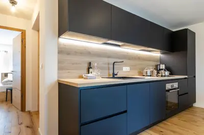 a kitchen with black cabinets and a blue sink at Casa Erika in San Lorenzo di Sebato