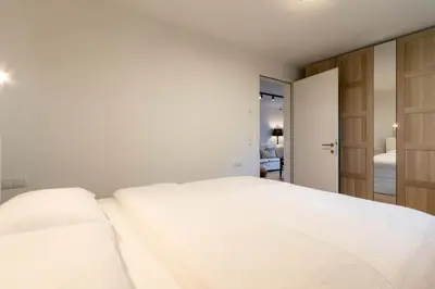 a white bedroom with a large bed and a door at Casa Fiammetta in Brunico