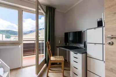 a room with a desk and a refrigerator and a window at Casa Waldheim in Brunico