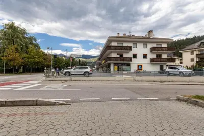 an empty street with a building and cars on the road at Casa Waldheim in Brunico