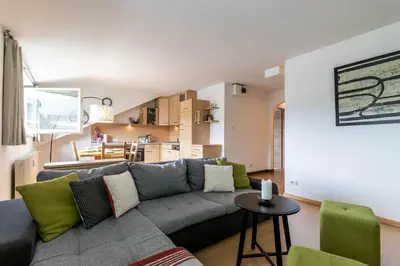 a living room with a gray couch and green chairs at Casa Waldheim in Brunico