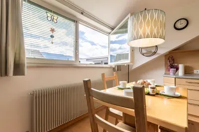 a dining room with a table and chairs and two windows at Casa Waldheim in Brunico