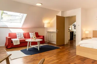 a room with a bed and a red couch and a table at Central Attic - Castle view in Brunico
