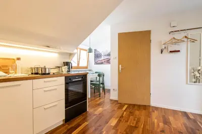a kitchen with white cabinets and a wooden floor at Central Attic - Castle view in Brunico