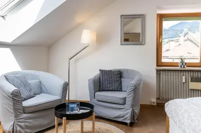 a living room with two chairs and a table at Central Attic - City view in Brunico