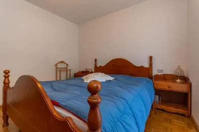a bedroom with a wooden bed with a blue blanket at Casa Blue Sky in Moena