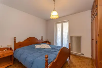 a bedroom with a bed with blue sheets and a window at Casa Blue Sky in Moena