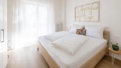 a white bedroom with a large bed with white sheets at Italyescapes Maia in Merano