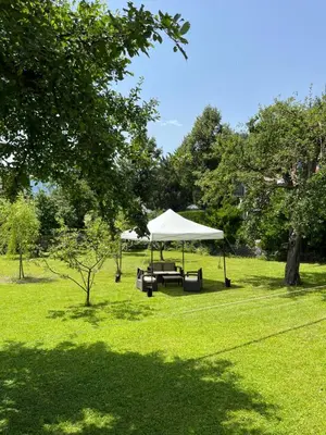 a picnic table with a white tent in a field at Dolomitihouse FAGHER in Fiera di Primiero