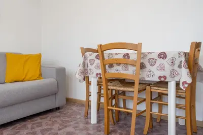 a dining room table with chairs and a couch at Dolomitihouse FAGHER in Fiera di Primiero