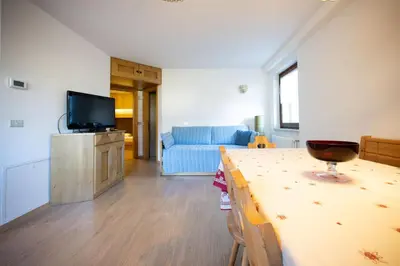 a living room with a table and a blue couch at Cesa te Val in Vigo di Fassa
