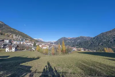 a green field with a small town in the mountains at Cesa te Val in Vigo di Fassa