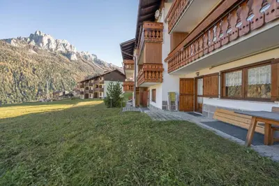 a house with a grassy yard next to a building at Cesa te Val in Vigo di Fassa