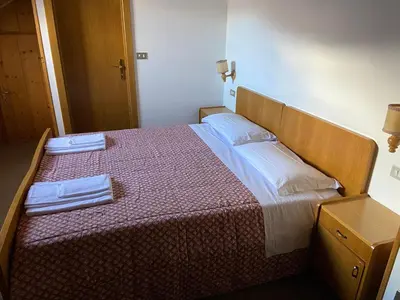 a bedroom with a bed with two towels on it at Dolomites Hotel La Meridiana in Moena