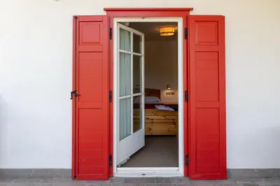 a red door leading into a room with a bedroom at Dolomites Hotel La Meridiana in Moena