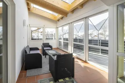 a room with windows and chairs and a table at Apartments Gasser in Rasun di Sopra