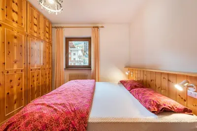 a bedroom with a large bed with red blankets at Delizioso appartamento trilocale a Moena in Moena