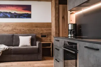 a living room with a couch and a kitchen at Biohof Untergröber in Braies