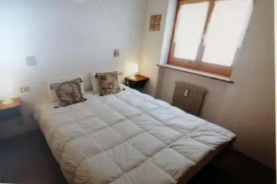 a bedroom with a large white bed with a window at La casa di Antonello Chiara Alessandro e Ginevra in Malga Ciapela