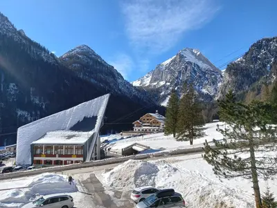 a snow covered mountain range with a building and cars at La casa di Antonello Chiara Alessandro e Ginevra in Malga Ciapela