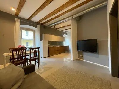 a living room with a dining table and a television at Haus Gugler in Bolzano