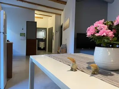 a white table with a vase of pink flowers on it at Haus Gugler in Bolzano