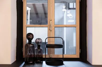 two glass vases sitting on a table in front of a window at Attica 54 Apartments Merano in Merano