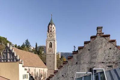 a clock tower in a town with a building at Attica 54 Apartments Merano in Merano