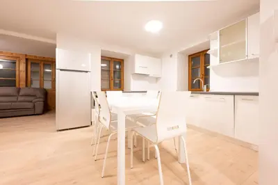 a white kitchen with a white table and chairs at Cesa Meida 2A in Pozza di Fassa