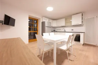 a kitchen and dining room with a white table and chairs at Cesa Meida 2B in Pozza di Fassa