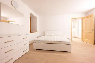a white bedroom with a bed and a dresser at Cesa Meida 2B in Pozza di Fassa