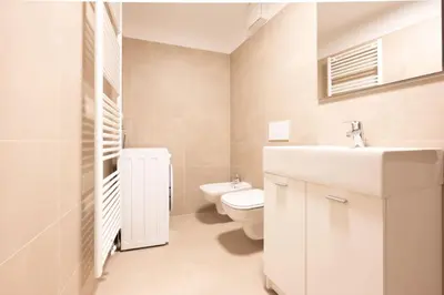 a white bathroom with a toilet and a sink at Cesa Meida 2B in Pozza di Fassa