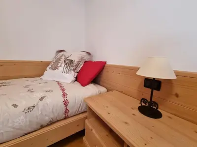 a bed with two pillows and a table with a lamp at Appartamento ai larici, rustico ed elegante in Varena