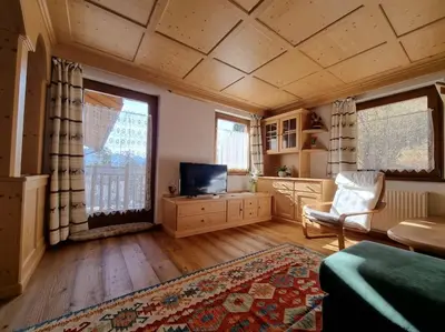 a living room with a tv and a couch and a chair at Appartamento ai larici, rustico ed elegante in Varena