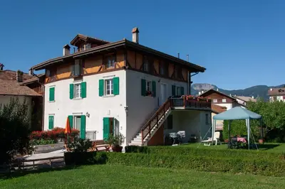a large white house with green windows and a roof at Appartamento Rosa in Coredo