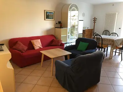 a living room with a red couch and chairs and a table at Appartamento Rosa in Coredo