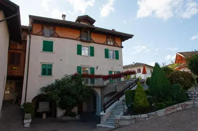 a large white building with green shutters and stairs at Appartamento Rosa in Coredo