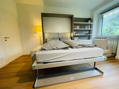 a large bed in a room with a shelf at Green View: il verde in città in Bolzano