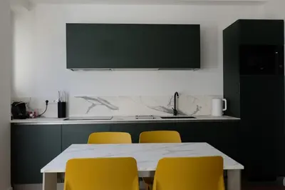 a kitchen with a table and four yellow chairs at Green View: il verde in città in Bolzano