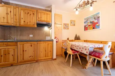 a kitchen with wooden cabinets and a table and chairs at Cesa Ariale in Canazei