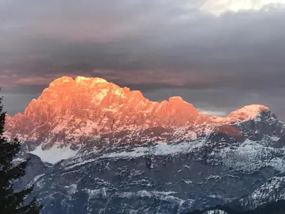 a snow covered mountain with the sun shining on it at Il nido dei gufi in Falcade