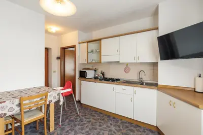 a kitchen with white cabinets and a table and a counter at Dolomitihouse VIEGHEL in Fiera di Primiero